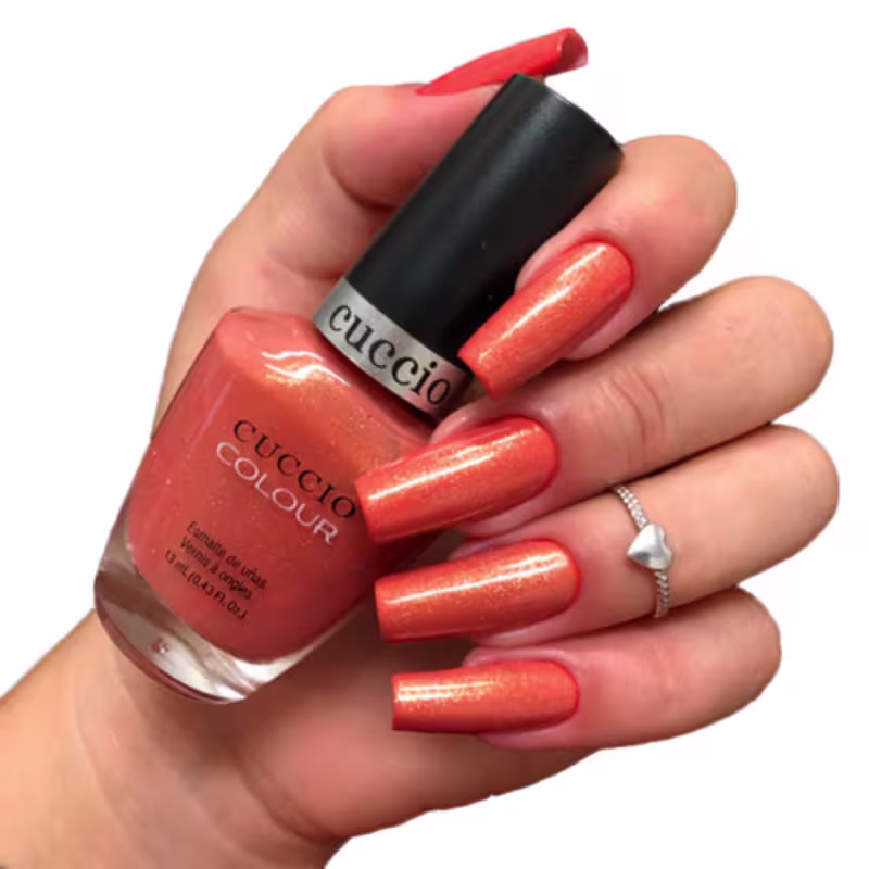Modelo com as unhas pintadas segurando o frasco do Cuccio Brasil Colour Blush Hour 1146 - Esmalte Cintilante 13ml.