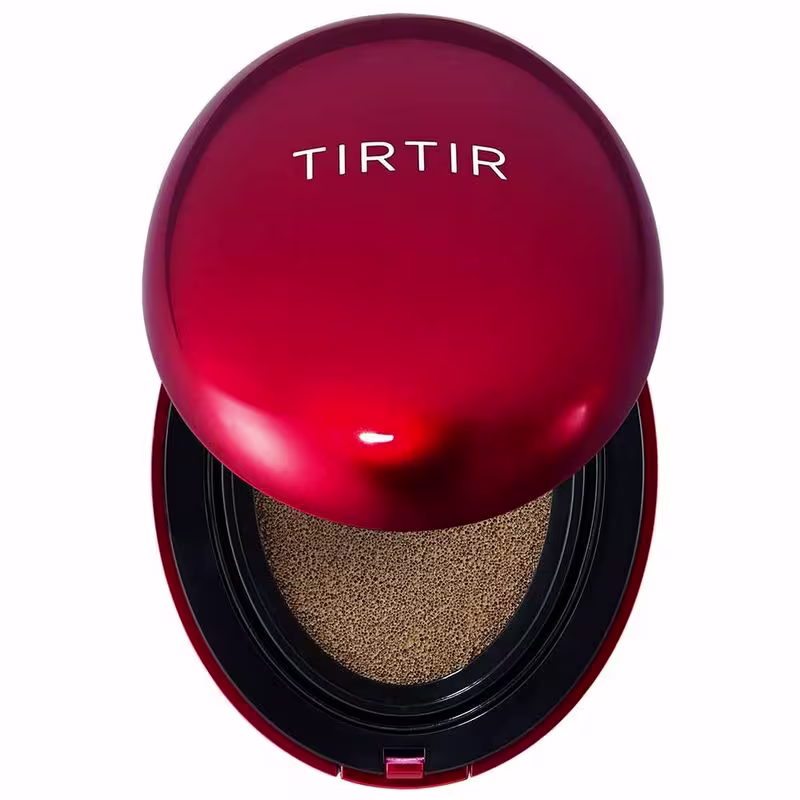 Trata-se de um produto de maquiagem da marca Tirtir, em uma embalagem redonda de cor vermelha com o nome da marca em destaque. O produto parece ser um tipo de base ou corretivo, com uma textura granulada em tom dourado visível em seu interior.