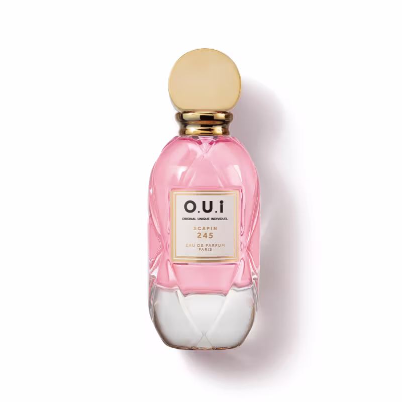 Frasco de perfume O.U.i. com design elegante e cores rosa e dourado. Rótulo com nome da marca e informações sobre a fragrância "Scapin 245". Embalagem de vidro com tampa dourada, apresentando uma aparência sofisticada e exclusiva.