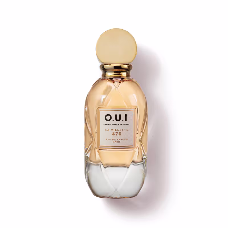Frasco de perfume O.U.i. La Villette 470, com design elegante e dourado, contendo líquido âmbar. O rótulo apresenta o nome da marca e a descrição "Eau de Parfum Paris".