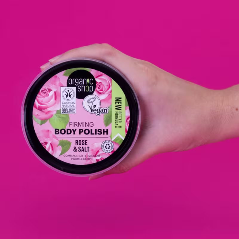 A imagem mostra uma mão segurando o produto sobre um fundo pink.