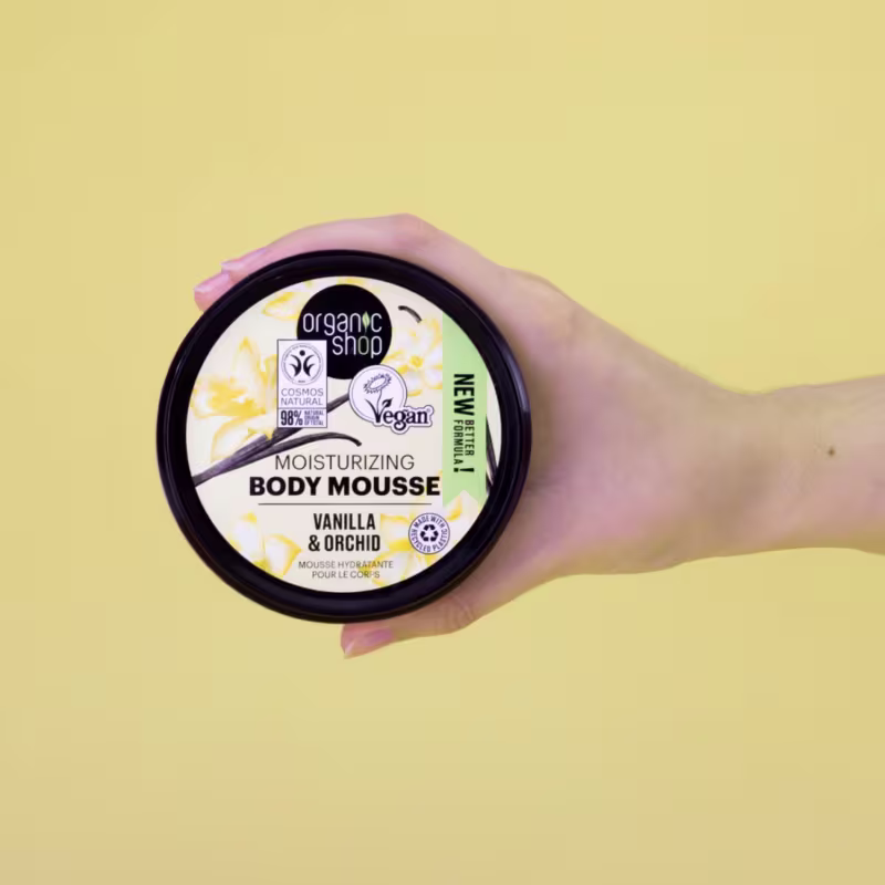 A imagem mostra uma mão segurando o produto sobre um fundo bege.