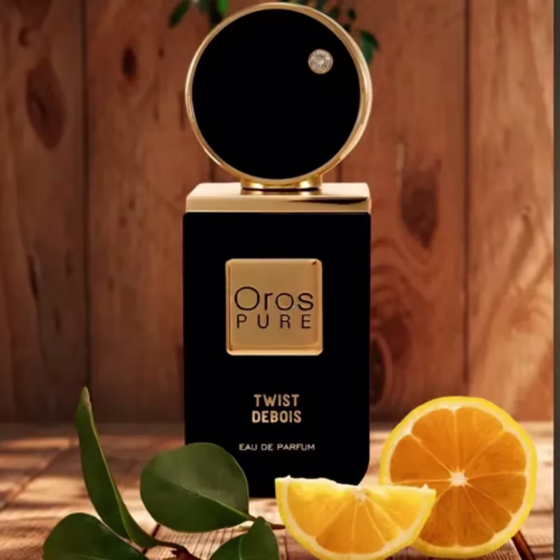 Ambiente de luxo e sofisticação com a marca Oros Pure e seu perfume Twist Debois. Fundo de madeira rústica, com folhas verdes e fatias de laranja, sugerindo uma atmosfera natural e refinada.