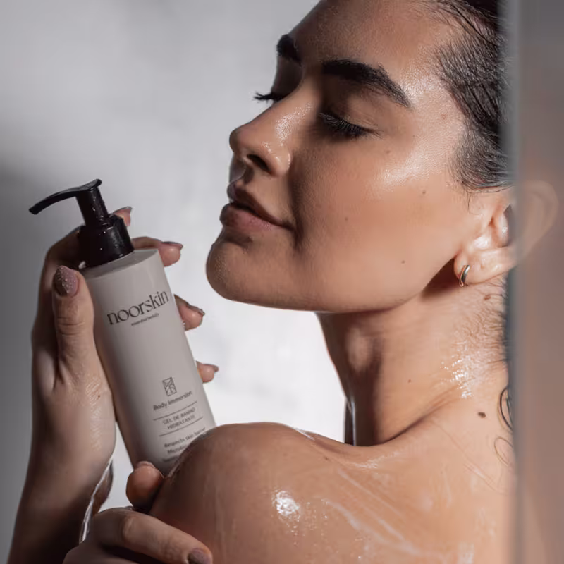 Modelo exibe a embalagem do Gel de Banho Noorskin Essential Beauty Body Immersion