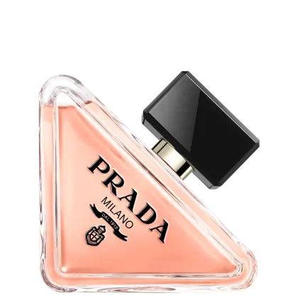 Frasco de perfume Prada com design triangular em vidro transparente, contendo líquido de cor rosa clara. O rótulo preto destaca o nome da marca "PRADA" em letras brancas.