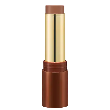 Bronzer em Bastão em embalagem cilíndrica. O estojo é de metal dourado com detalhes em tom de marrom. A parte superior e inferior são de cor cobre fosco. A embalagem tem um design elegante e sofisticado.