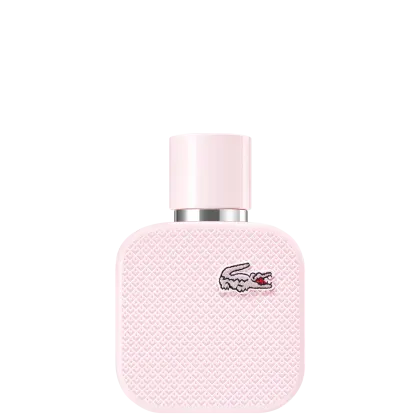 A imagem mostra um frasco de perfume da marca Lacoste. O frasco é retangular, com cantos arredondados e acabamento texturizado em relevo, todo rosa claro, e com o desenho de um crocodilo, símbolo da marca, no canto superior direito.