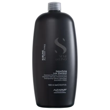 A imagem mostra o shampoo Semi di Lino Sublime Detoxifying Low 1 litro, da marca Alfaparf Milano. Apresenta o rótulo com o nome Semi di Lino - Detoxifying Low Shampoo.  A embalagem preta com o logo e informações em branco dá um visual sofisticado.