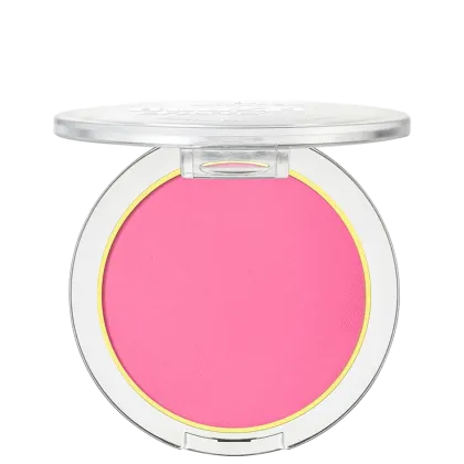 A imagem mostra um blush compacto de cor rosa pink em uma embalagem plástica transparente. O blush tem um acabamento fosco e está disposto em um estojo redondo. Em volta do pó compacto rosa, há um aro amarelo que realça a cor do produto.
