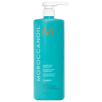 A imagem mostra o Shampoo Purificante Clarify 1L da marca Moroccanoil. Embalagem plástica na cor azul turquesa, com letras brancas e pretas e logotipo da marca em laranja. O frasco tem uma bomba dosadora branca na parte superior.