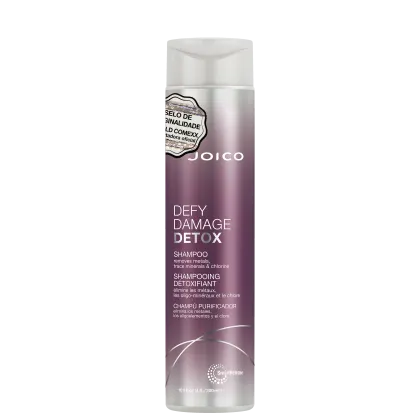 Shampoo detox Defy Damage da marca Joico. Embalagem cilíndrica roxa com detalhes prateados. Rótulo indicando que remove metais, minerais traço e cloro dos cabelos. Volume de 10.1 fl oz / 300ml.