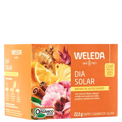 A imagem mostra a embalagem do chá em uma caixa retangular laranja com imagens de frutas cítricas, especiarias e flores. Texto em português descrevendo os ingredientes.