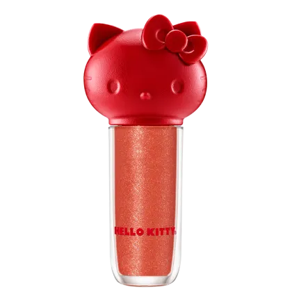 Maquiagem em formato cilíndrico com a cabeça da personagem Hello Kitty como tampa. A parte superior é vermelha com detalhes em relevo que representam os olhos, orelhas e laço da Hello Kitty. É possível ver a cor do produto pelo corpo transparente.