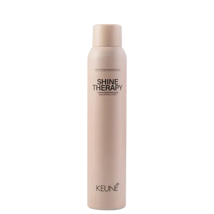 A imagem mostra o produto Shine Therapy da marca Keune. Embalagem cilíndrica na cor bege claro. Rótulo com o nome do produto "Shine Therapy" e descrição "Luminously finishing spray" (Spray de acabamento luminoso) em letras escuras.