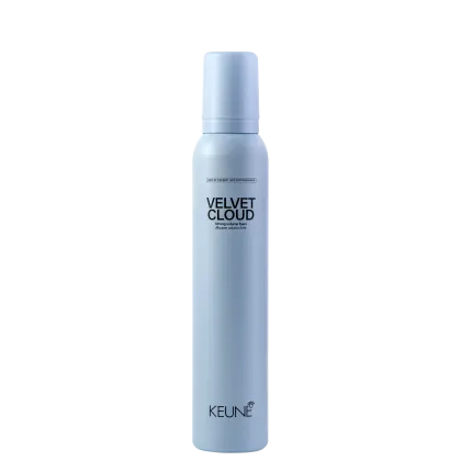 A imagem mostra a Mousse Volumadora Velvet Cloud da marca Keune. É apresentado em um frasco cilíndrico branco azulado opaco. Exibe o nome do produto "Velvet Cloud" em letras pretas maiúsculas, seguido da descrição "Mousse volume foam" em letras menores.