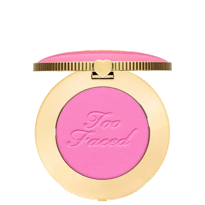 Blush compacto de maquiagem com embalagem redonda dourada. A tampa superior é rosa com a inscrição "Too Faced" em letras cursivas. Um pequeno coração dourado adorna o centro da tampa.