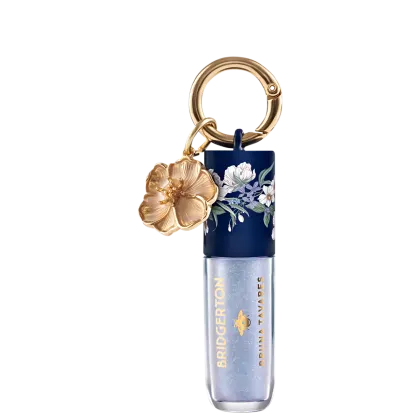 Embalagem de gloss labial da marca Bruna Tavares com textura suave e brilho, na cor Diamond, acompanhada de pingente dourado em formato de flor.