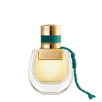 Frasco de perfume dourado com tampa e faixa verde, rótulo com a marca "NOMADE", embalagem de vidro com detalhes em relevo.