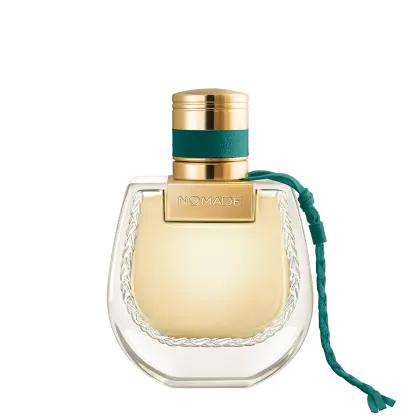 Frasco de perfume dourado com tampa e faixa verde, rótulo com a marca "NOMADE", embalagem de vidro com detalhes em relevo.