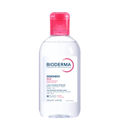 Frasco de água micelar da marca Bioderma, da linha Sensibio H2O, para peles sensíveis. Embalagem de plástico transparente com tampa rosada, contendo 250 ml do produto.
