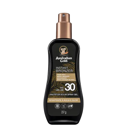 Embalagem âmbar com detalhes dourados, formato de frasco spray. Rótulo indica "Instant Bronzer", fator de proteção solar FPS 30, resistente à água e suor. Apresenta o logotipo da marca com um coala.