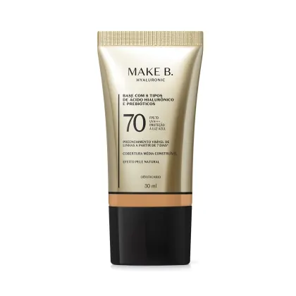 Tubo de base facial da marca Make B. com 8 tipos de ácido hialurônico e prebióticos, FPS 70, proteção UVA/UVB e efeito pele natural. Embalagem branca e dourada com rótulo informativo.