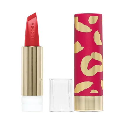 Na imagem há a case de um batom. Ela tem um padrão de manchas abstratas em rosa vibrante e dourado metálico. Esse design moderno e sofisticado com cores vivas é característico de uma linha de cosméticos glam e de luxo.