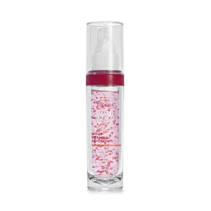 A imagem mostra um frasco pequeno, cilíndrico, transparente com tampa também transparente, visto de frente. O rótulo tem fundo rosa claro com detalhes em vermelho, exibindo o nome do produto, marca e volumetria com letras rosa e branca,