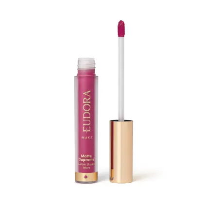 Batom Líquido Matte Supreme em embalagem transparente com tampa dourada e aplicador do tipo bastão. Produto com design minimalista e rótulo dourado no frasco.