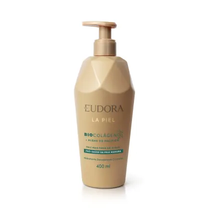 Embalagem plástica transparente em tom bege e dourado com bomba dosadora na parte superior. Rótulo com texto em verde. Design minimalista com nome da marca e linha em destaque em cor dourada mais brilhante que a da embalagem.
