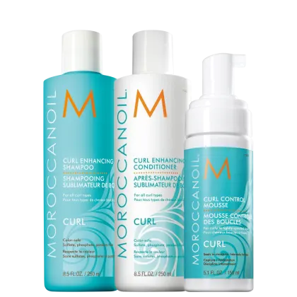 Produtos para cabelos cacheados da marca Moroccanoil. Inclui um shampoo de 250ml, um condicionador de 250ml e uma mousse capilar de 150ml. Todos os frascos têm o logotipo "M" laranja da marca. As cores predominantes são turquesa, branco e laranja.