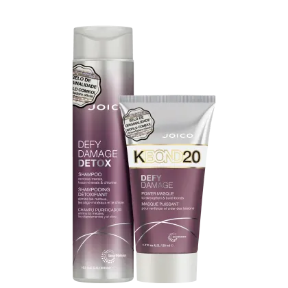 Shampoo e máscara capilar da linha Defy Damage Detox da marca Joico. O shampoo vem em um frasco cilíndrico branco com detalhes em roxo.  A máscara capilar é apresentada em um tubo branco com detalhes roxos.