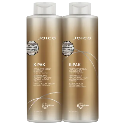 São dois frascos de plástico dourado de 1 litro cada, contendo shampoo e condicionador reconstrutores da linha K-Pak da marca Joico. Os frascos têm formato cilíndrico e tampas brancas.