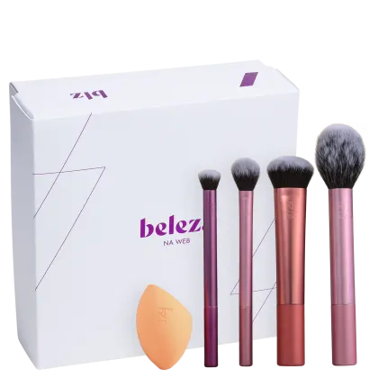 A imagem mostra uma caixa branca presenteável da marca Beleza na Web e quatro pincéis de diferentes tamanhos e uma esponja de maquiagem da Real Techniques.