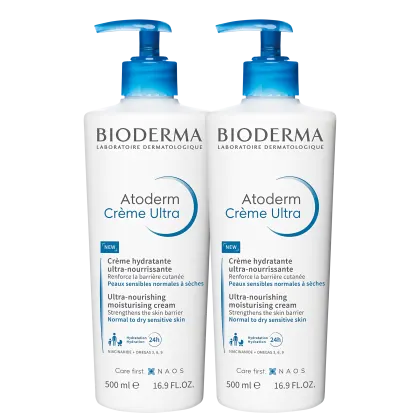 Dois frascos brancos com bombas doseadoras azuis da marca Bioderma, contendo o produto "Atoderm Crème Ultra",  de 500ml cada, um creme hidratante ultra-nutritivo para pele sensível normal a seca.