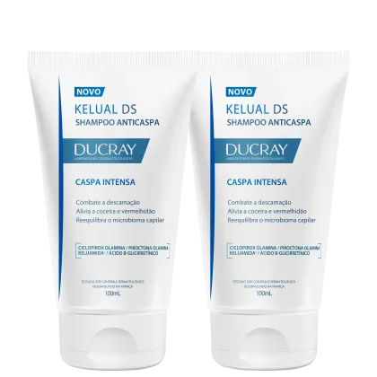 Dois frascos de shampoo anticaspa da marca Ducray, com rótulos em azul e branco indicando "Caspa Intensa" e "Kelual DS Shampoo Anticaspa". Cada frasco possui 100mL de produto.