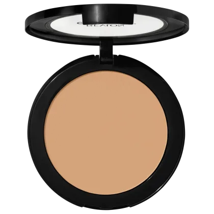 Pó compacto de maquiagem Revlon em embalagem redonda preta. A superfície do pó tem uma cor bege claro uniforme. A tampa transparente exibe o logotipo "Revlon" em letras brancas. O produto apresenta um design minimalista e elegante.
