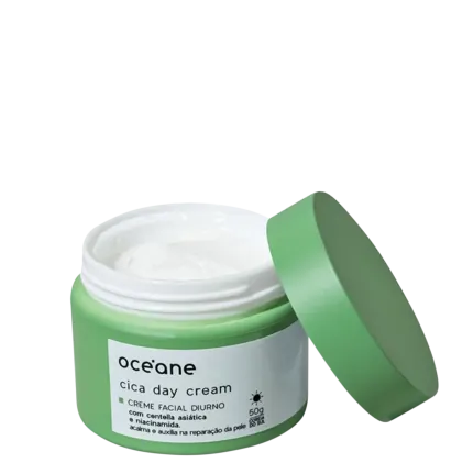 A imagem mostra a embalagem do creme hidratante facial Océane Cica Day Cream. O produto vem em um pote de plástico na verde com um rótulo branco e letras pretas descrevendo nome, marca e ativos. A embalagem está aberta com a tampa reclinada ao pote.