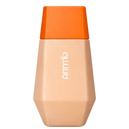 Frasco de maquiagem de cor bege com tampa laranja, com o nome "Quimia" impresso no corpo do produto. O formato é geométrico e a embalagem possui uma aparência moderna e minimalista.