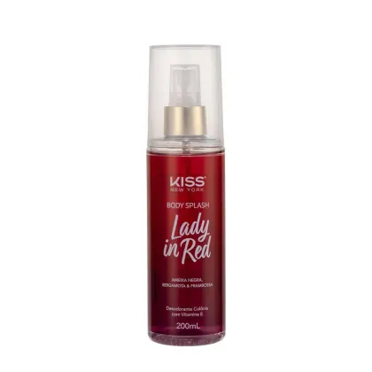A imagem mostra o Body Splash em uma embalagem com cores vermelho e dourado, apresentando o logotipo Kiss New York. A tampa é transparente e traz um detalhe dourado na válvula spray.