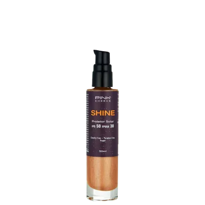 Frasco de protetor solar da marca Pink Cheeks, com o nome "Shine" e informações sobre FPS 50 e FPUVA 30. O produto é de cor laranja e possui um rótulo preto com detalhes em branco. A embalagem é de plástico e possui um aplicador tipo bomba.
