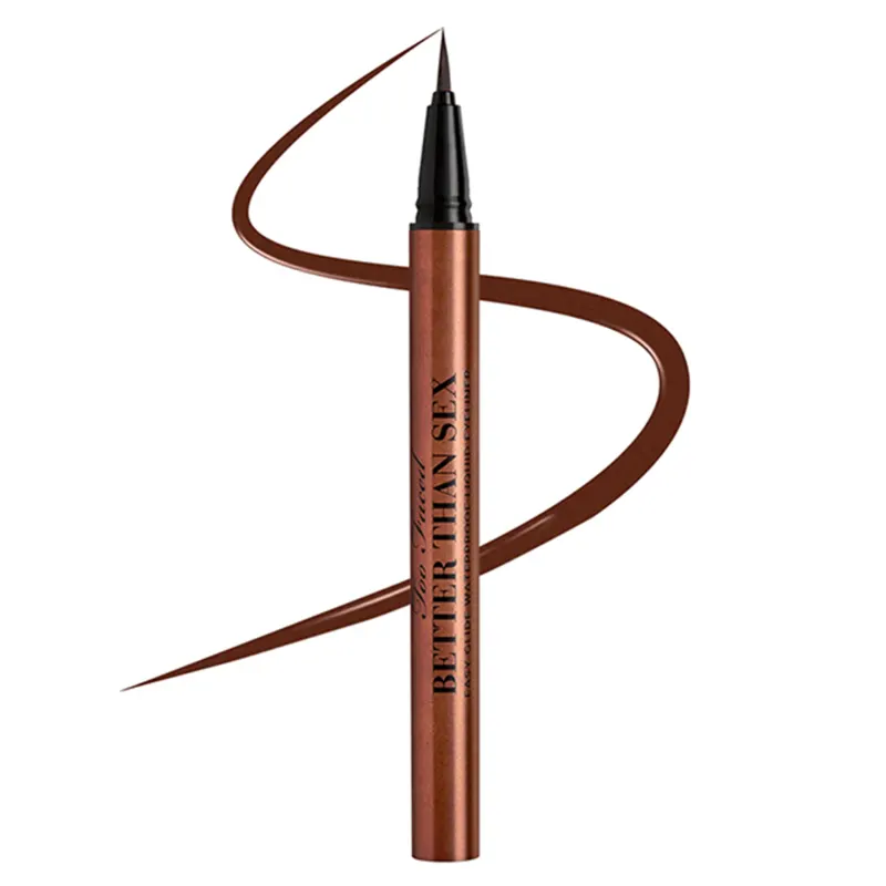 Delineador líquido para olhos Too Faced. Embalagem alongada e fina em tons de marrom metálico. Rótulo com o nome do produto "Better Than Stix" impresso na lateral da embalagem. A ponta do delineador forma uma linha sinuosa que se estende pela lateral.