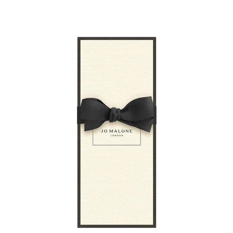 A caixa do perfume Jo Malone London, com uma fita preta em laço na parte superior. A caixa é branca com o logotipo da marca impresso.