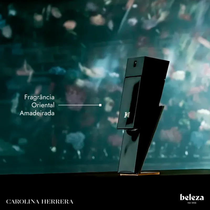 Frasco preto de perfume Carolina Herrera com rótulo "Fragrância Oriental Amadeirada" em fundo desfocado de folhas verdes.