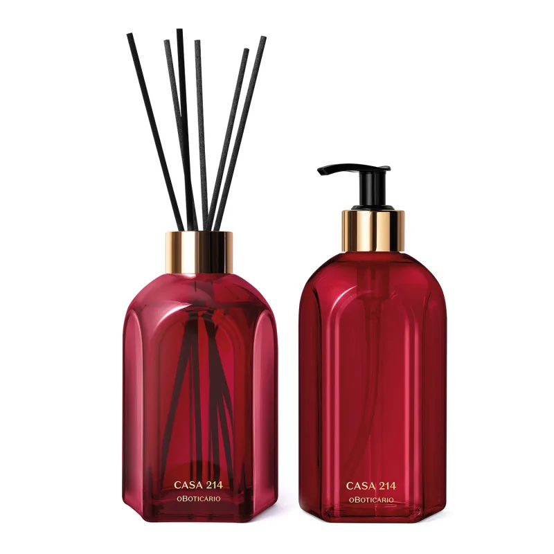 Dois vidros vermelhos da marca Casa 214 Gardênia Imperial: um difusor de ambientes com varetas e o outro com bico dosador preto contendo sabonete líquido.