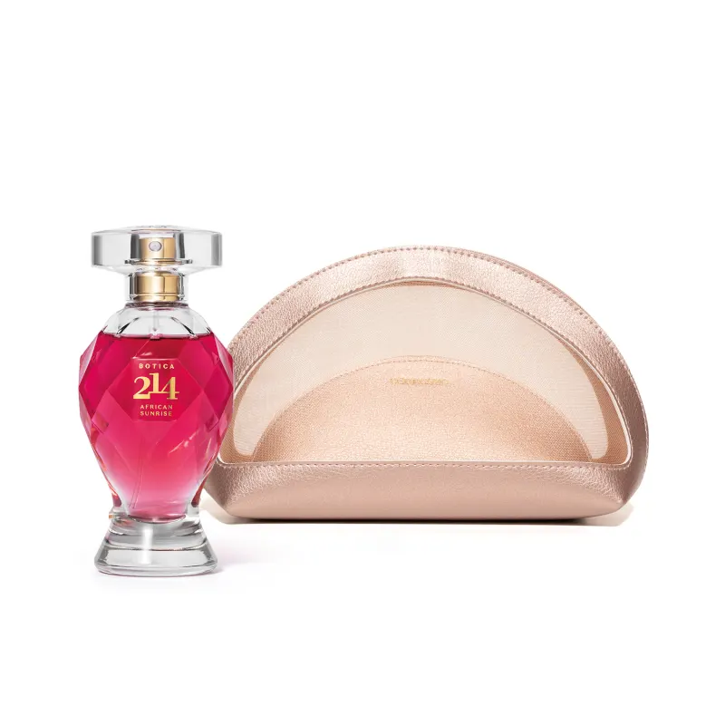 Vidro lapidado em formato de taça com líquido rosa, letras e pulverizador dourados e tampa transparente de Eau de Parfum Botica 214 African Sunrise e um nécessaire rosa metalizado com o nome da marca O Boticário gravado na frente do produto.