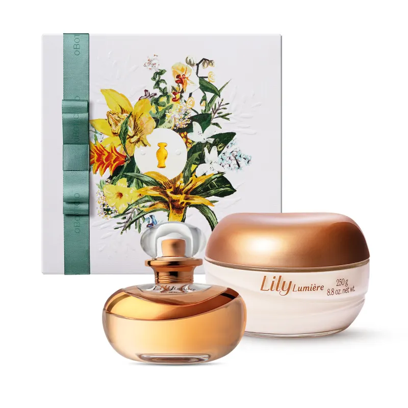 A imagem mostra um kit que contém um elegante vidro do Eau de Parfum Lily Lumiére transparente e com detalhes em tom de dourado, um pote de creme corporal de vidro com tampa dourada da mesma marca e uma caixa de presente com ilustração floral.