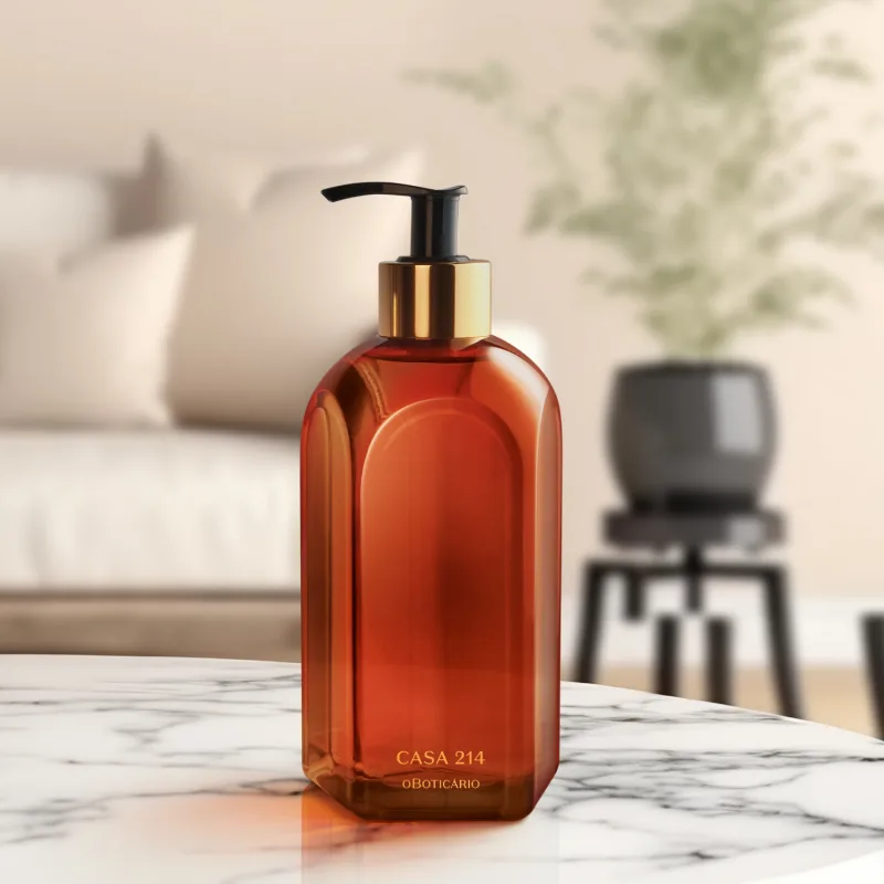 Vidro laranja de tampa dosadora preta com detalhe e letras douradas de sabonete líquido Casa 214 Vanilla Sublime sobre superfície de mármore, com objetos escuros desfocados ao fundo, em ambiente iluminado e minimalista.