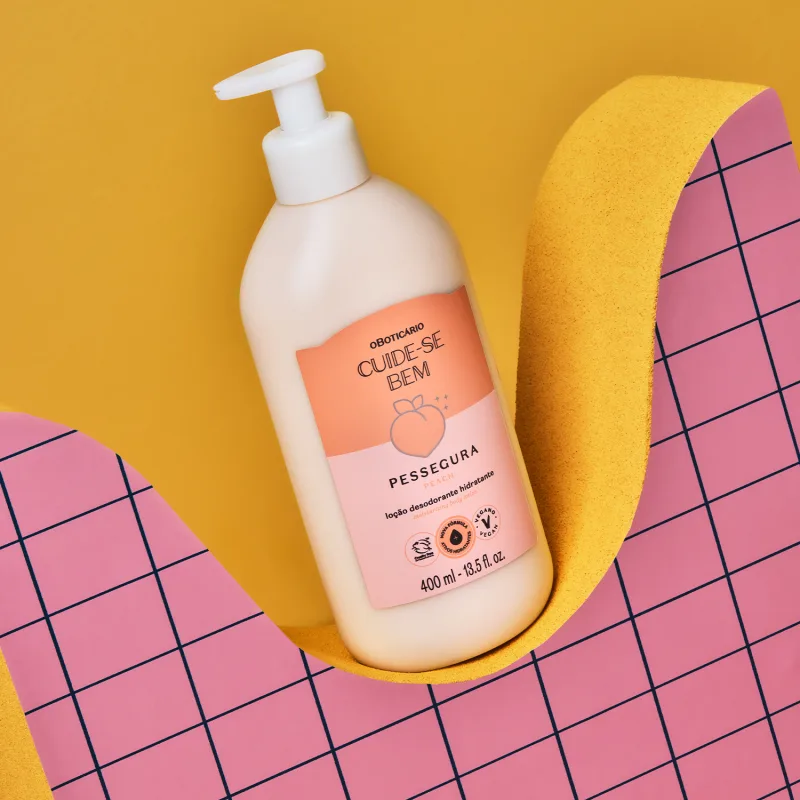 Embalagem de item de cuidados com a pele Cuide-se Bem Pessegura nas cores branco e laranja sobre superfície amarela ondulada e fundo quadriculado rosa com linhas pretas.