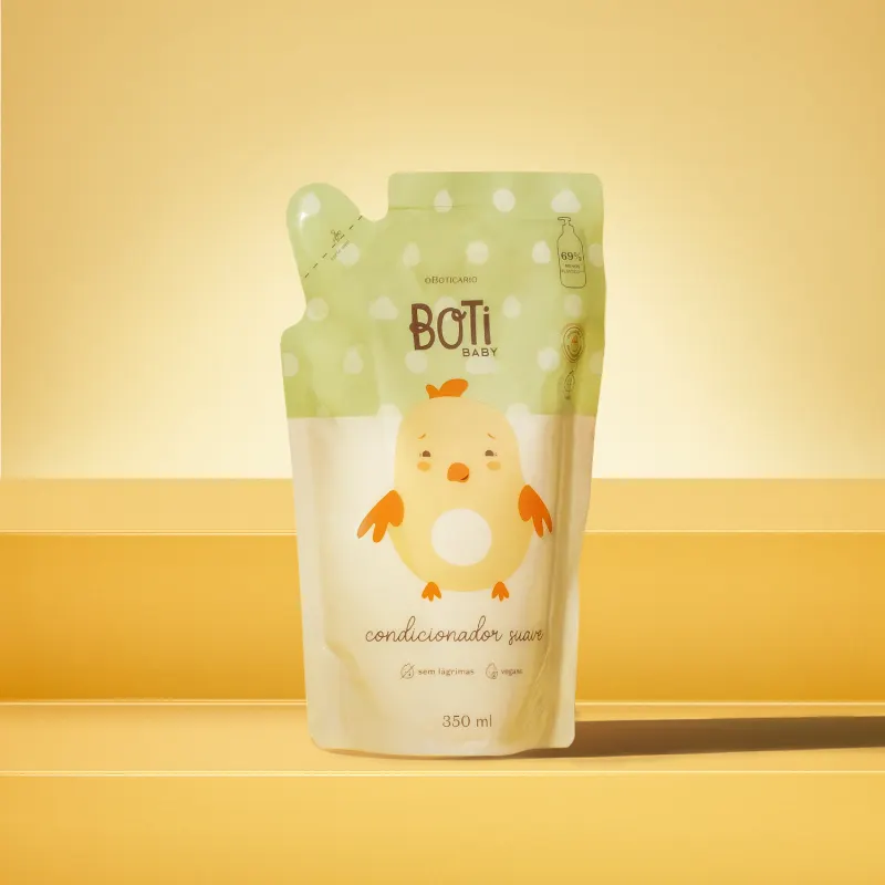 Refil de condicionador suave da marca Boti Baby em forma de sachê nas cores rosa e amarelo claro com ilustração de passarinho amarelo com detalhes laranjas. O fundo e superfície são em tons de laranja.